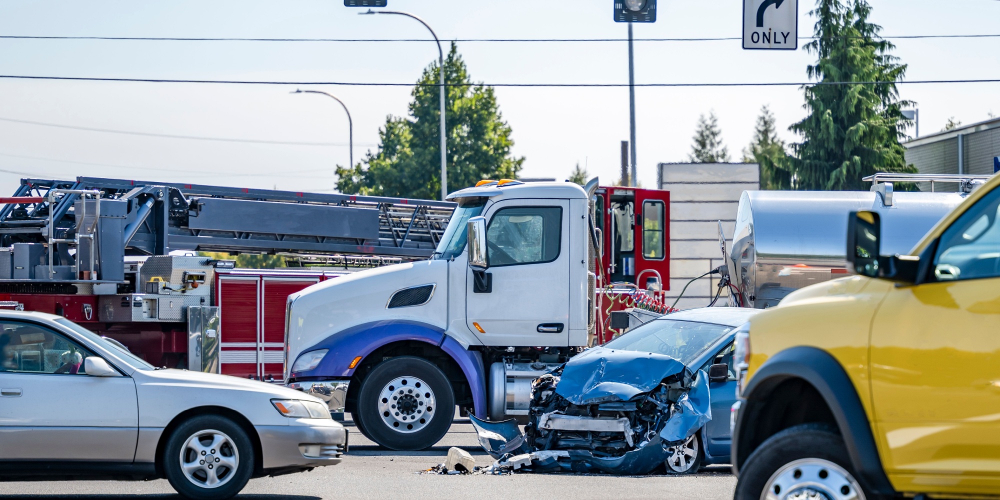 Damaged cars after a car accident crash involving a big rig semi truck with semi trailer at a city street crossroad intersection with traffic light and rescue services to help the injured