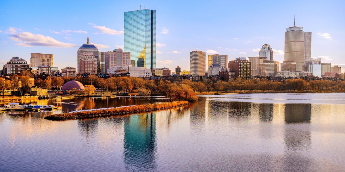 Boston City Skyline over the Charles River in Massachusetts, USA. A tranquil riverscape of Back Bay with golden illuminated wintery foliage in New England.