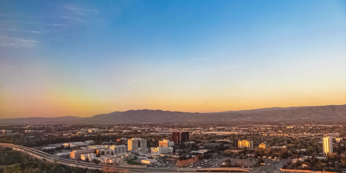 Skyline cityscape of highrise skyscrapers and highway toll road in San Jose California during sunset in aerial view