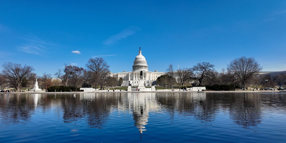 United States Capitol Building reflecting on a clear winter day with a few clouds in the distance. National Mall in Washington D.C.